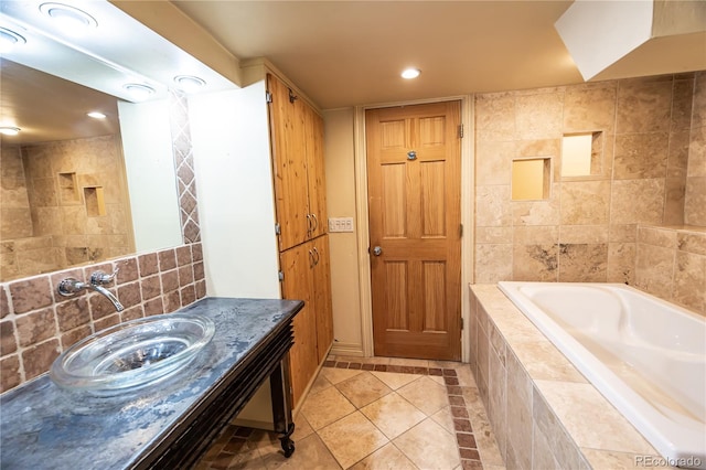 bathroom featuring tile patterned flooring, vanity, tiled tub, and tile walls