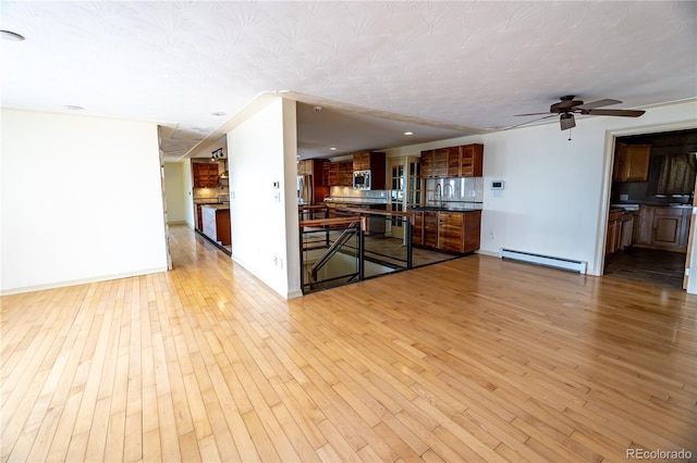 unfurnished living room featuring a baseboard radiator, ceiling fan, a textured ceiling, and light hardwood / wood-style flooring