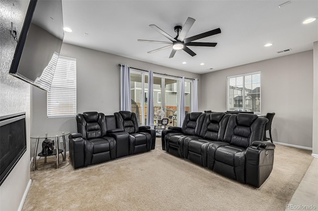 cinema featuring a tile fireplace, light carpet, and ceiling fan