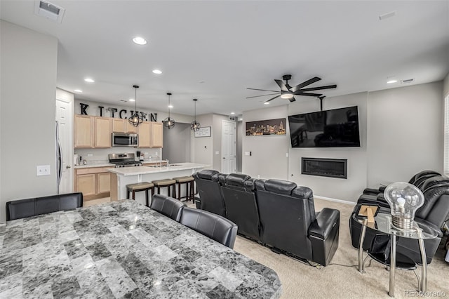 dining area with ceiling fan, light colored carpet, and sink