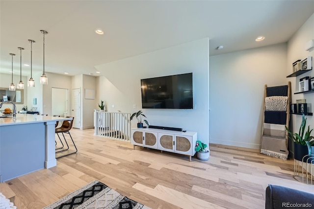 living room featuring baseboards, recessed lighting, and light wood-style floors