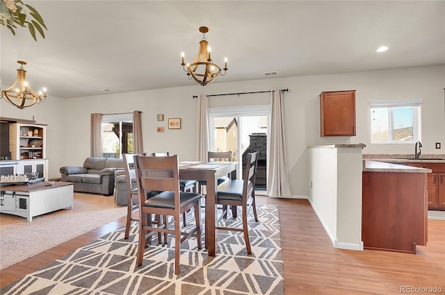 dining space featuring a notable chandelier, visible vents, and light wood-type flooring
