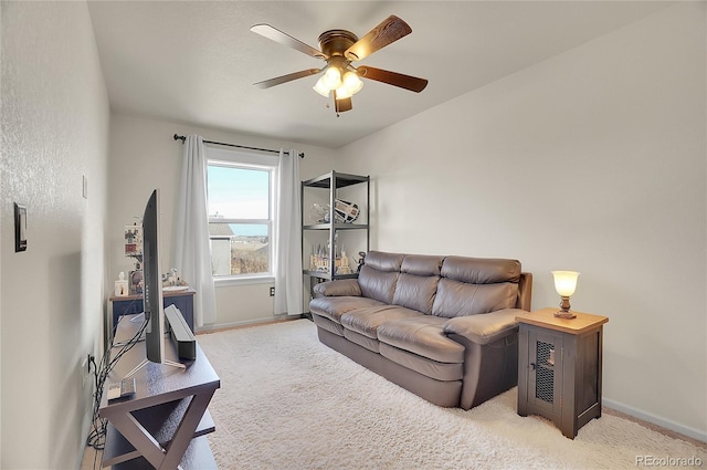 living area with light carpet, a ceiling fan, and baseboards