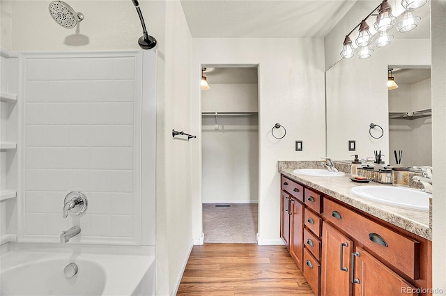 full bathroom with double vanity, wood finished floors, shower / bath combination, and a sink