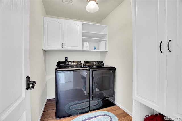 washroom with washer and clothes dryer, visible vents, baseboards, wood finished floors, and cabinet space