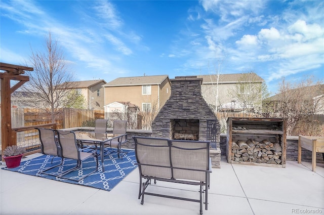 view of patio with fence, an outdoor stone fireplace, a storage unit, and outdoor dining space