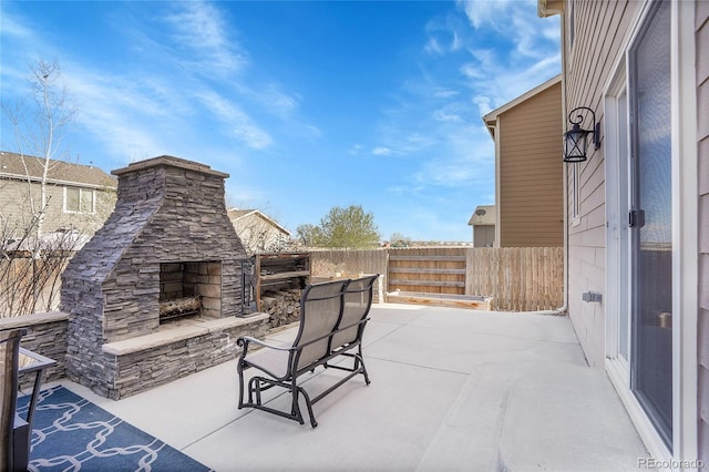 view of patio / terrace with fence and an outdoor stone fireplace