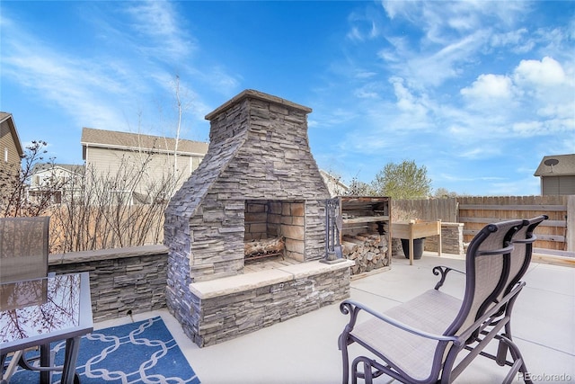 view of patio / terrace featuring fence and an outdoor stone fireplace