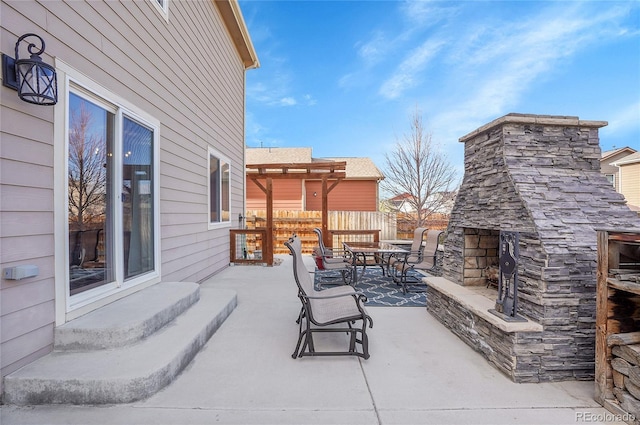 view of patio with fence, an outdoor stone fireplace, and outdoor dining area