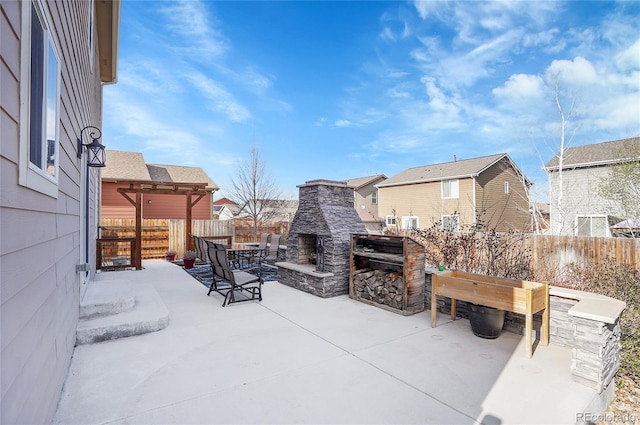 view of patio with fence, an outdoor stone fireplace, and a residential view