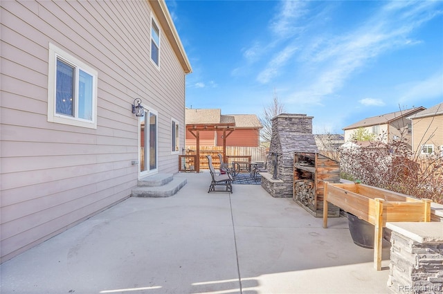 view of patio / terrace featuring an outdoor stone fireplace and fence