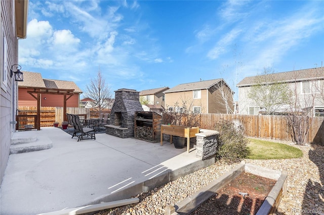 exterior space with an outdoor stone fireplace, a fenced backyard, a patio, and a residential view