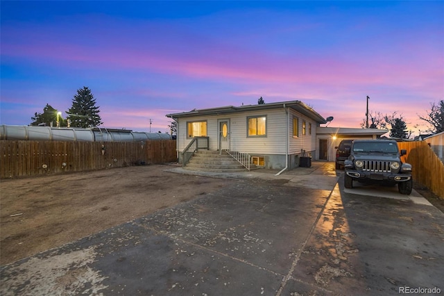 view of front of home featuring driveway, central AC unit, and fence