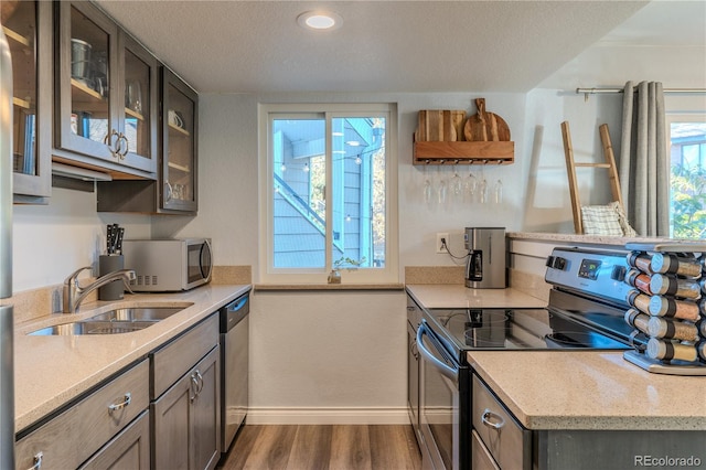 kitchen featuring stainless steel appliances, sink, light stone countertops, a textured ceiling, and dark hardwood / wood-style flooring