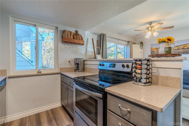 kitchen featuring kitchen peninsula, ceiling fan, a textured ceiling, wood-type flooring, and electric stove