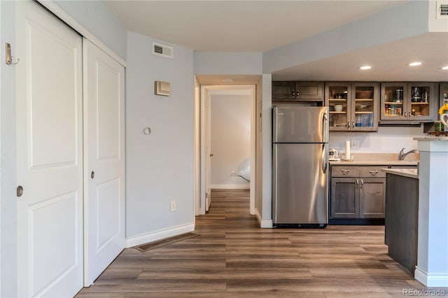 kitchen featuring dark wood-type flooring, dark brown cabinetry, sink, and stainless steel refrigerator