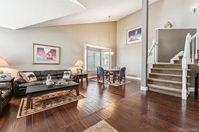 living area with visible vents, baseboards, wood-type flooring, an inviting chandelier, and stairs