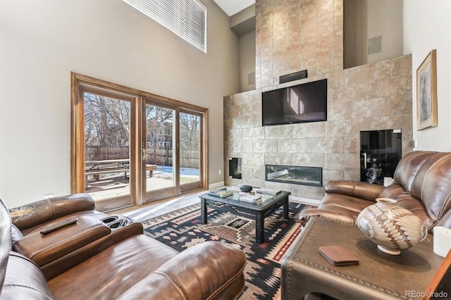 living area with a high ceiling and a tiled fireplace