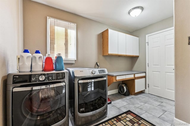 washroom featuring cabinet space, baseboards, washer and dryer, and light tile patterned flooring