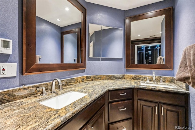 bathroom featuring a textured wall, double vanity, and a sink