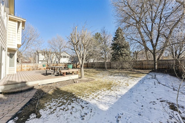 yard layered in snow featuring a fenced backyard and a deck