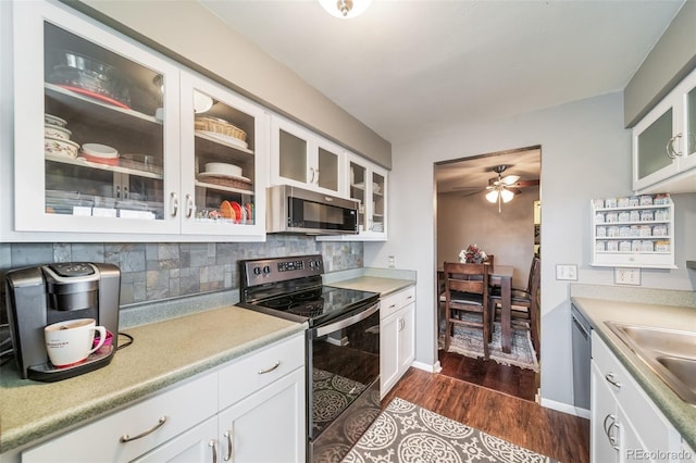 kitchen featuring ceiling fan, dark hardwood / wood-style flooring, backsplash, white cabinets, and stainless steel appliances