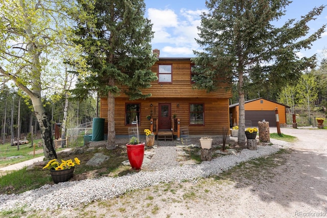8600 S Warhawk Rd, Conifer, CO 80433 - rustic home featuring a detached garage, an outbuilding, a chimney, and covered porch