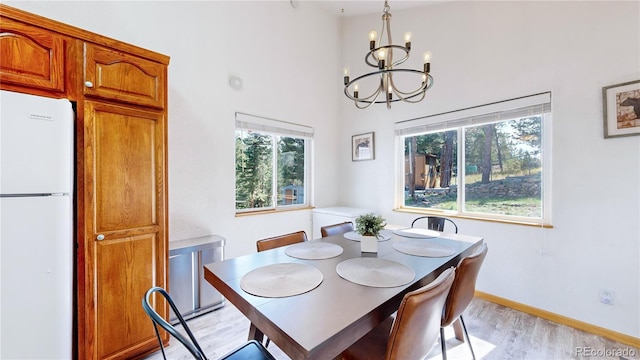 11348 Ranch Elsie Rd, Golden, CO 80403 - dining space featuring an inviting chandelier, a high ceiling, baseboards, and light wood finished floors