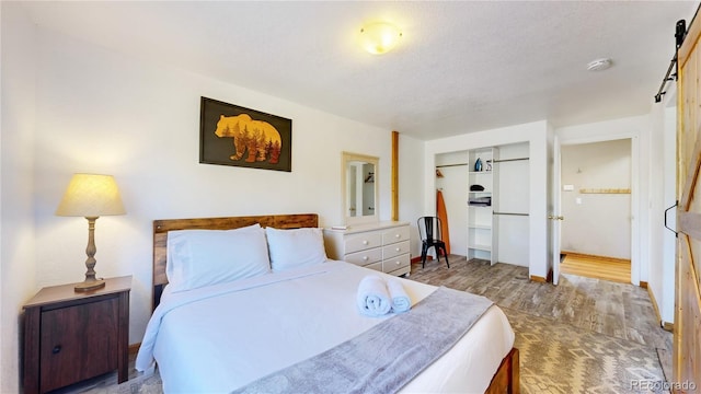 11348 Ranch Elsie Rd, Golden, CO 80403 - bedroom with baseboards, a closet, a barn door, and wood finished floors