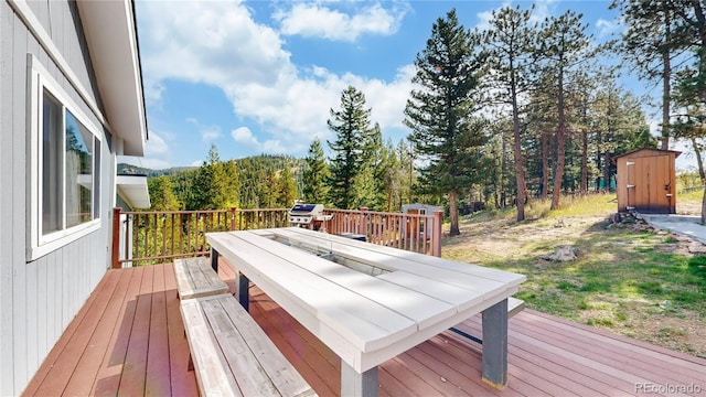11348 Ranch Elsie Rd, Golden, CO 80403 - deck with outdoor dining area, a forest view, an outbuilding, and a storage unit