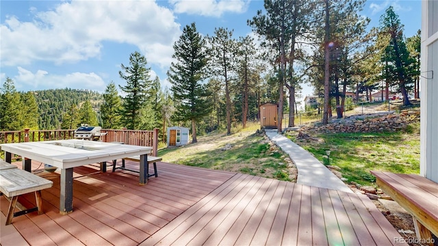 11348 Ranch Elsie Rd, Golden, CO 80403 - wooden terrace with outdoor dining area, grilling area, an outbuilding, a forest view, and a shed