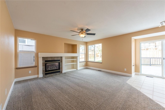 unfurnished living room featuring a tile fireplace, light carpet, and ceiling fan