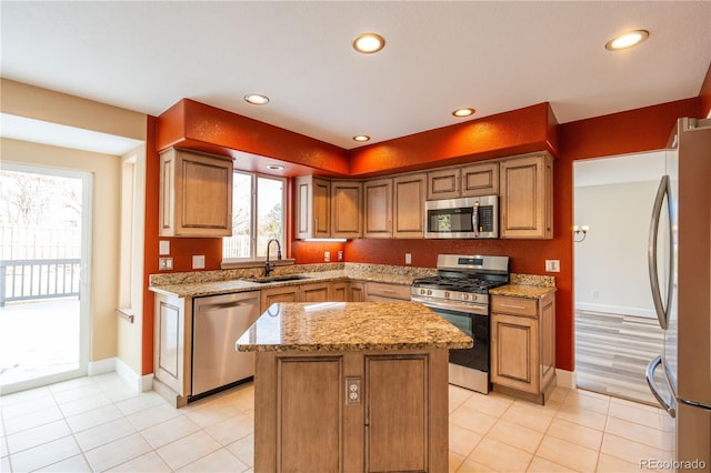 kitchen featuring stainless steel appliances, light stone counters, a wealth of natural light, and sink