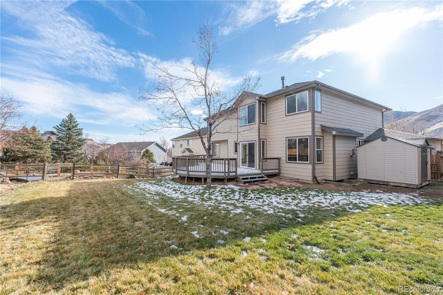 rear view of property featuring a lawn, a storage unit, and a deck with mountain view