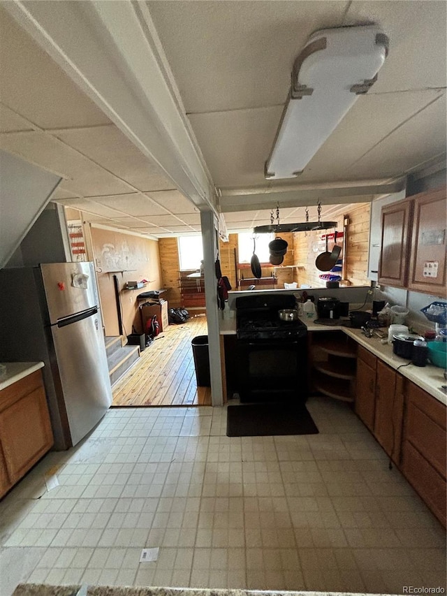 kitchen featuring light tile patterned floors, black range oven, and stainless steel refrigerator