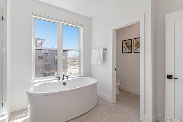 bathroom with tile patterned flooring, a bathtub, toilet, and plenty of natural light