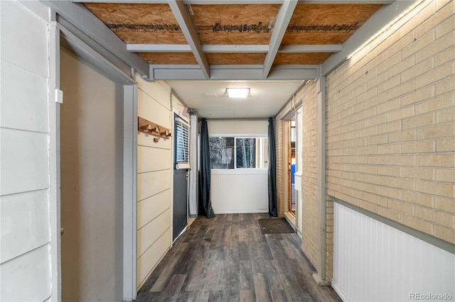 hall with brick wall and dark wood-type flooring