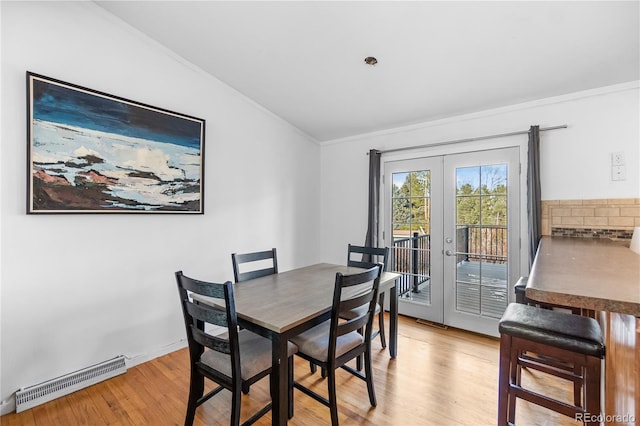 dining area with ornamental molding, light wood-type flooring, and french doors