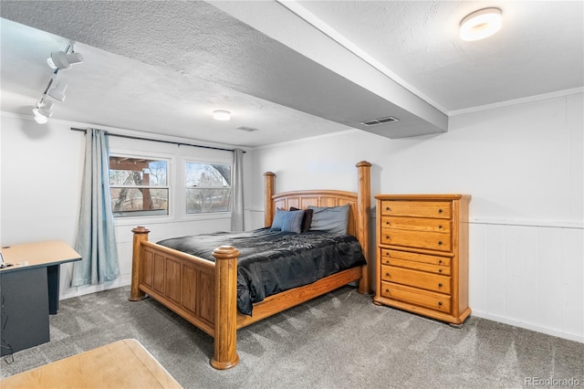 carpeted bedroom with rail lighting, ornamental molding, and a textured ceiling