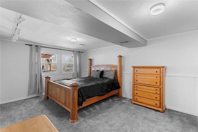 carpeted bedroom with ornamental molding, rail lighting, and a textured ceiling