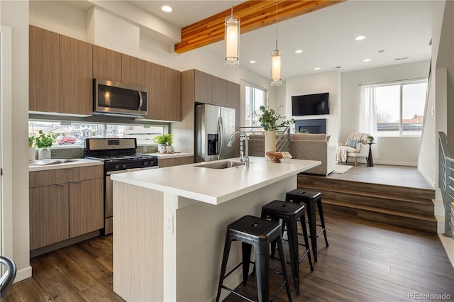 kitchen with dark wood-style flooring, a sink, a kitchen breakfast bar, appliances with stainless steel finishes, and beam ceiling