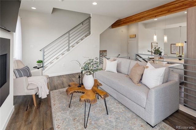 living area with baseboards, wood finished floors, stairs, beam ceiling, and recessed lighting