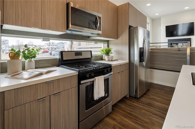 kitchen featuring dark wood-style floors, decorative backsplash, stainless steel appliances, and light countertops