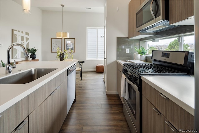 kitchen featuring dark wood finished floors, appliances with stainless steel finishes, light countertops, and a sink