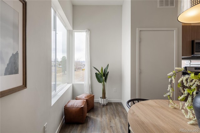 dining space with plenty of natural light, wood finished floors, visible vents, and baseboards