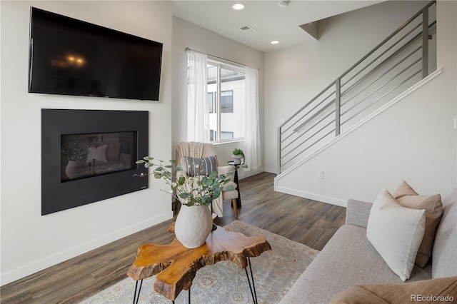 living area featuring baseboards, visible vents, wood finished floors, stairs, and recessed lighting