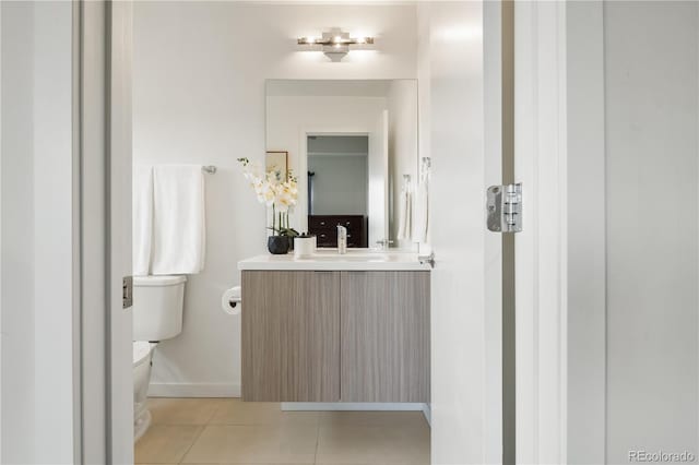 half bathroom featuring vanity, tile patterned flooring, toilet, and baseboards