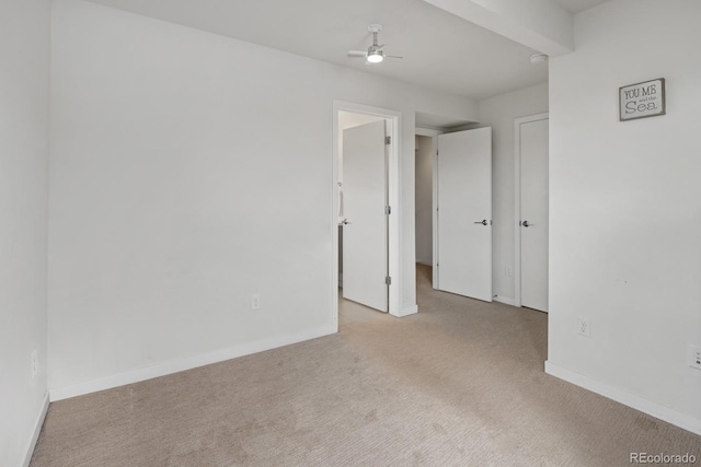 carpeted spare room with baseboards and a ceiling fan