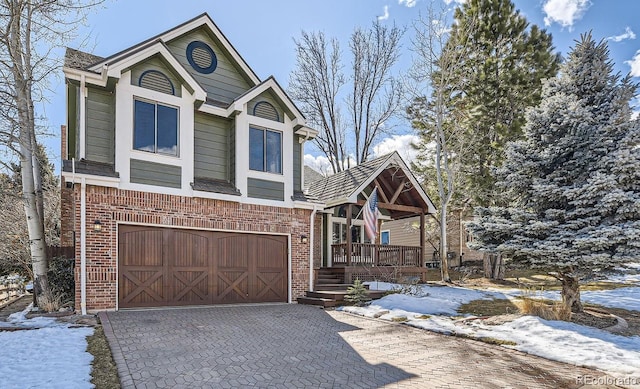 view of front of home featuring brick siding, covered porch, decorative driveway, and a garage