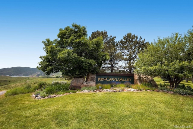 community sign featuring a mountain view and a yard